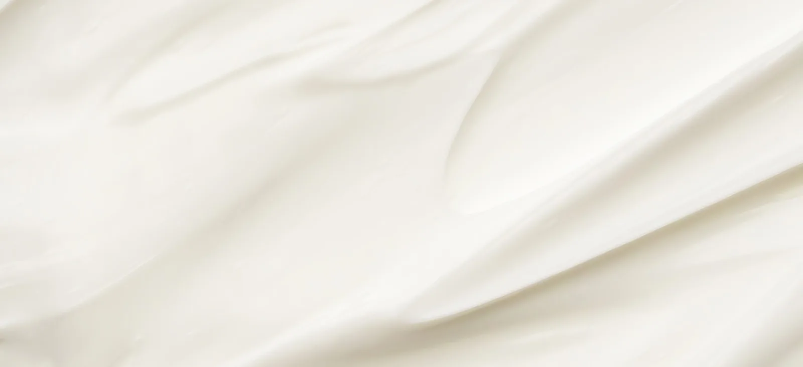 A close macro of smooth white cream, the soft lactonic texture that milk perfumes are built to smell like.